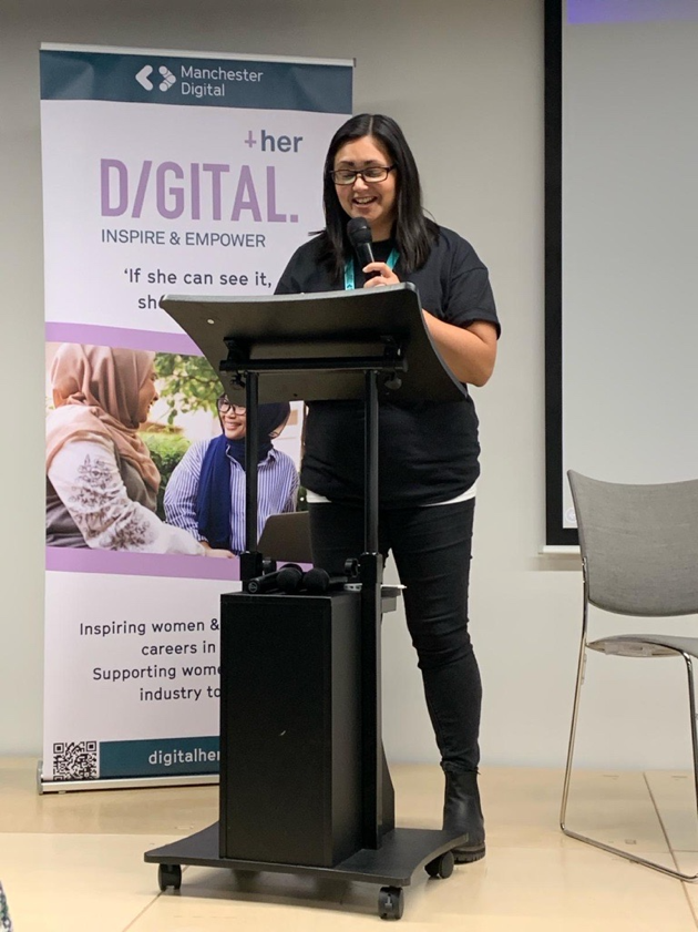 A person standing at a podium with a microphone

Description automatically generated